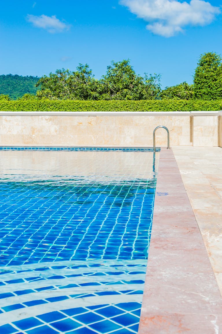 Bright and tranquil poolside scene, capturing a turquoise swimming pool under a clear blue sky.