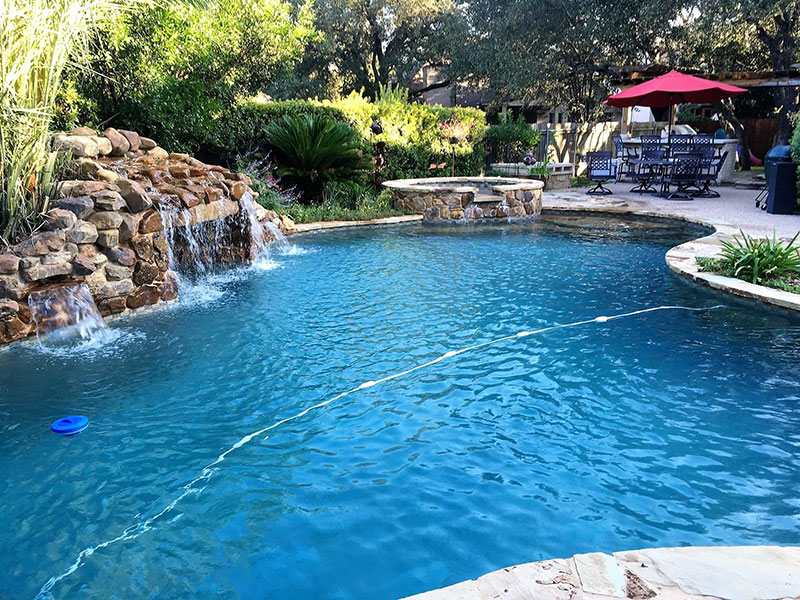 swimming pool surrounded by lush trees and a small waterfall